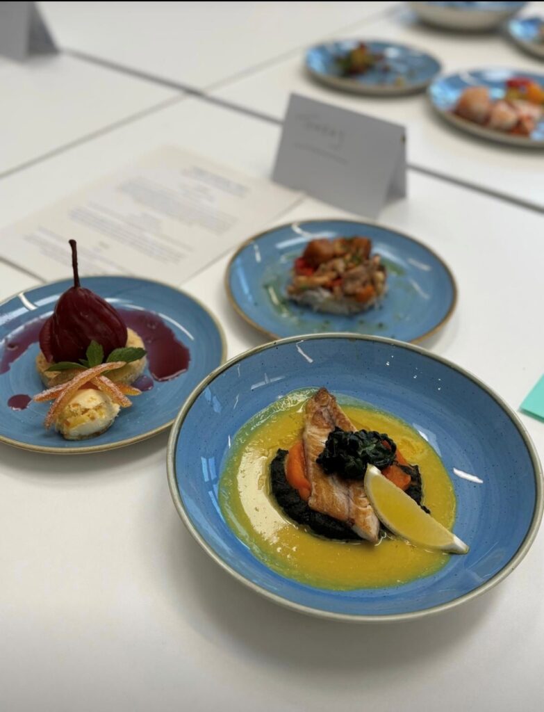 Three dishes with a red lentil sisig (a Filipino dish), Brixham mackerel with sweet potato, kale and a turmeric and coconut sauce finished off with a poached pear with a Devon flag, with a candied orange peel, clotted cream and a fruit and ‘Cornish’ red wine reduction.