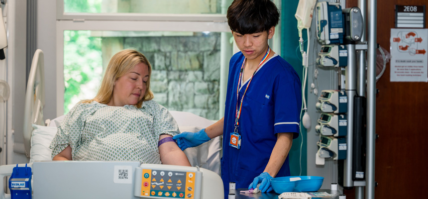 Patient lying in a hospital bed under the care of a male healthcare professional