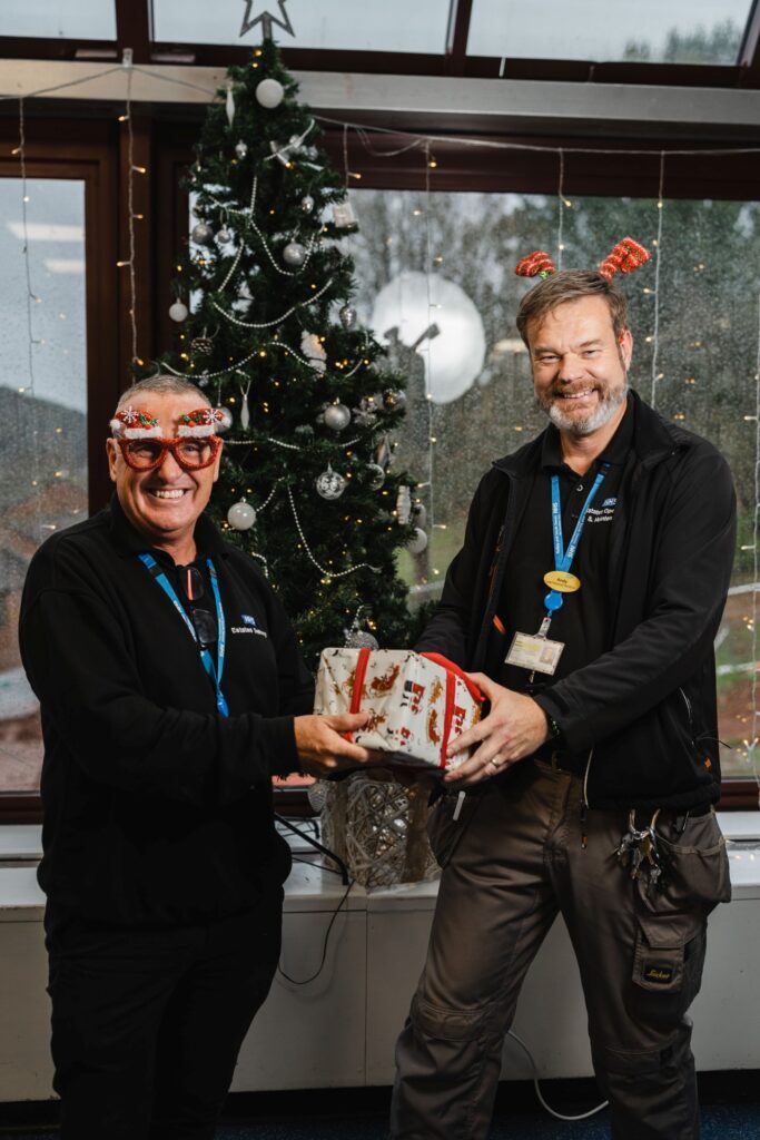 Two of our colleagues holding gifts, standing by the tree in Bayview restaurant.