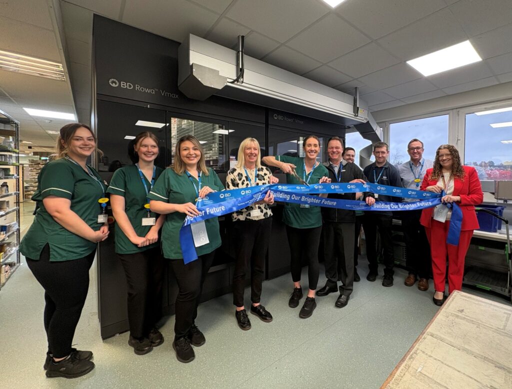 Some of our pharmacy colleagues in front of our new pharmacy robot, holding ribbon.