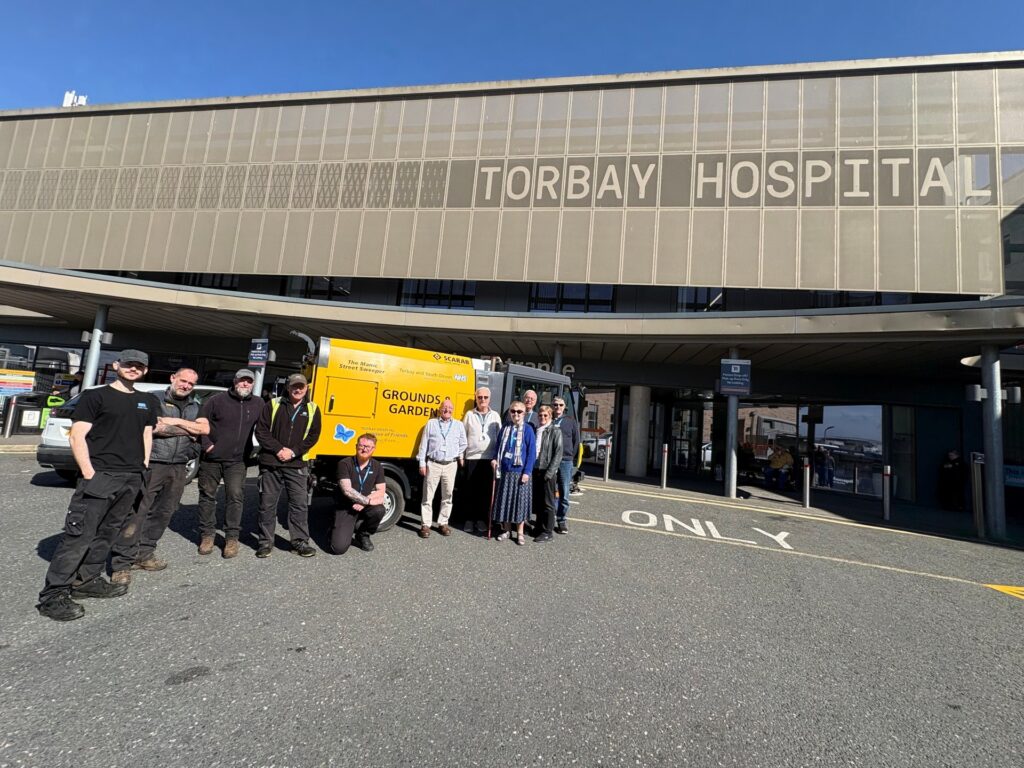 Members of Torbay Hospital League of Friends and the gardens and grounds team standing in front of our new roadsweeper.