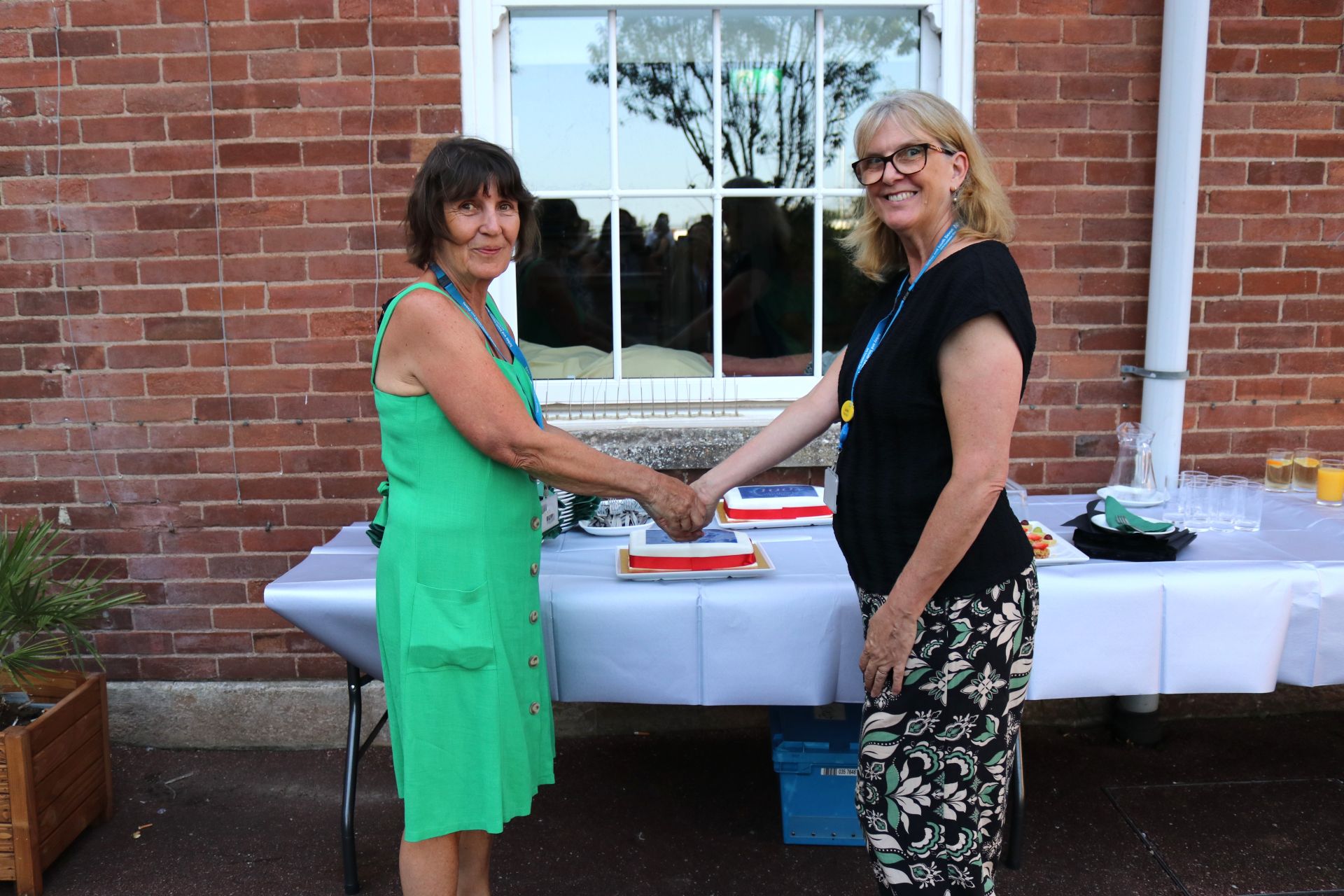 Two women cutting the cake, celebrating 100 years since the foundation stone was laid at Torbay Hospital