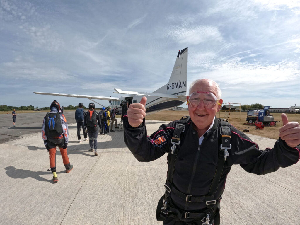 John Payne with with both thumbs up as he is about to board the air plane behind him.