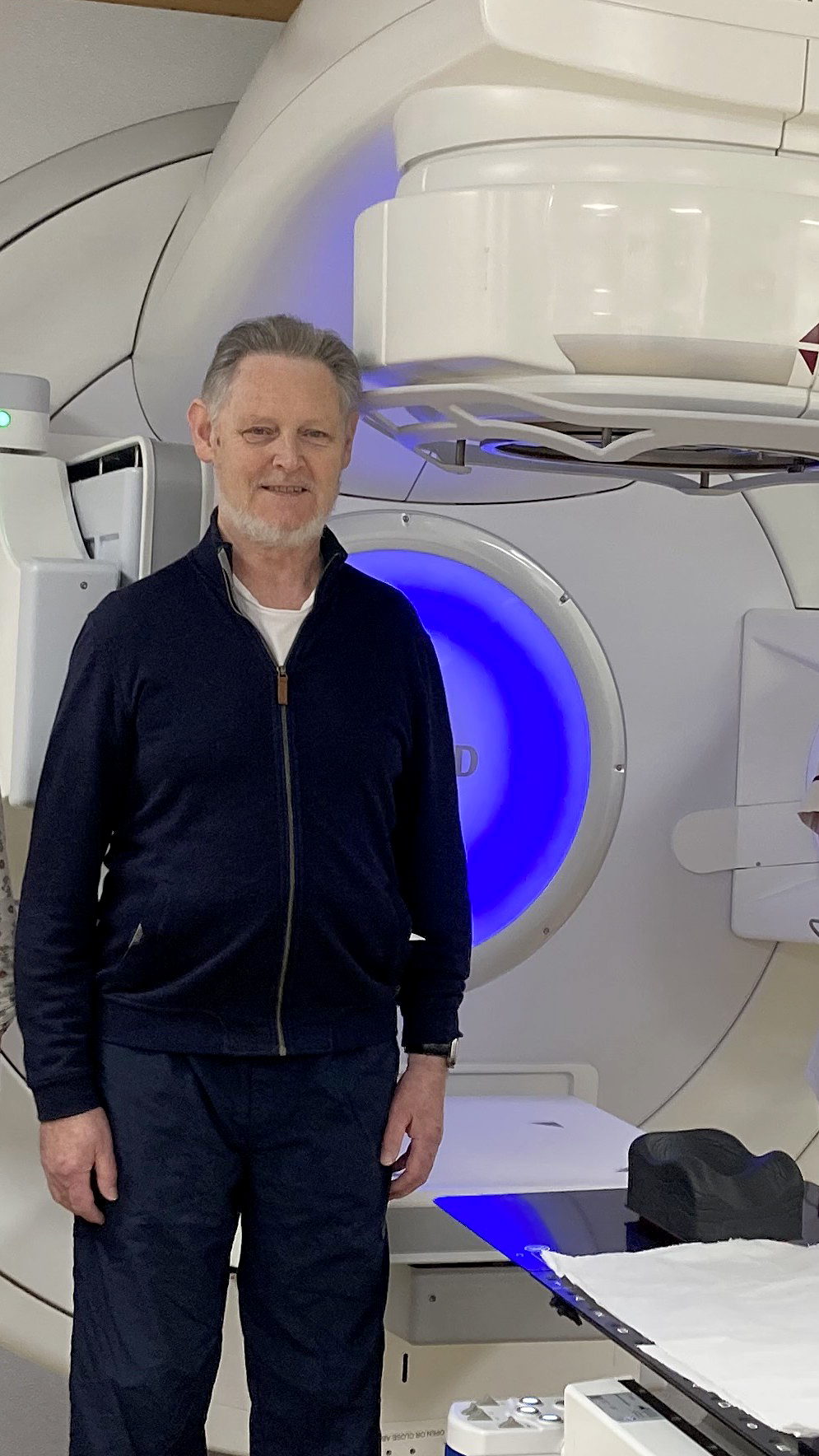 Stephen Dwyer-Lapthorne standing next to the Stereotactic ablative radiotherapy (SABR) device