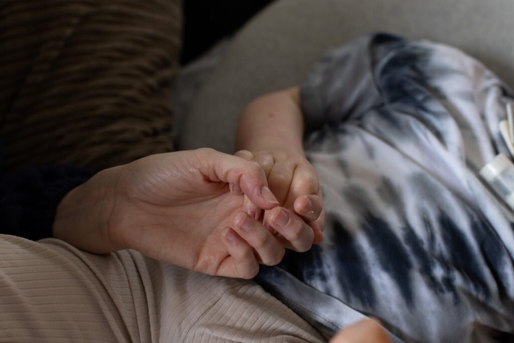 Close up photo of an adult's hand holding a child's hand
