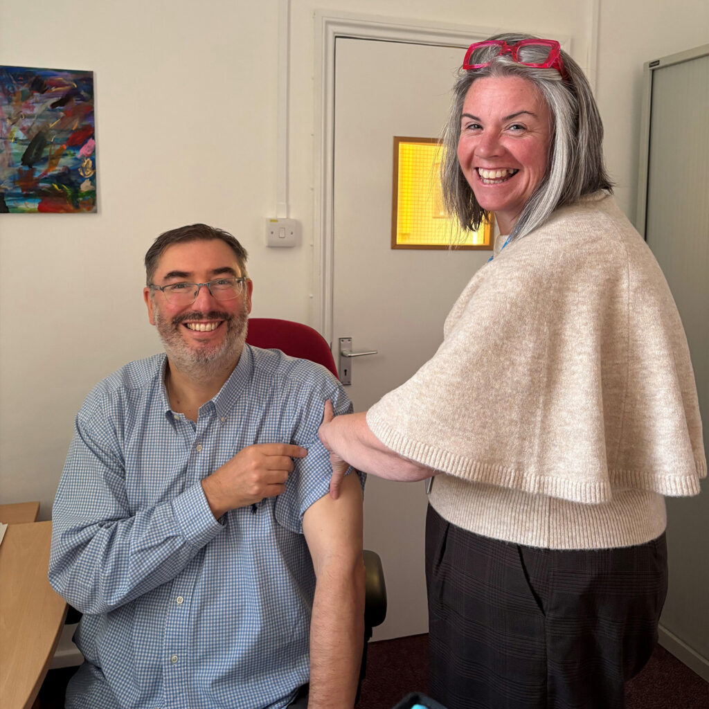 Simon Tapley receiving his flu vaccination from Natalie Herring